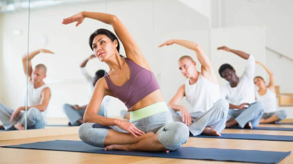 Woman practicing Hatha yoga postures with group